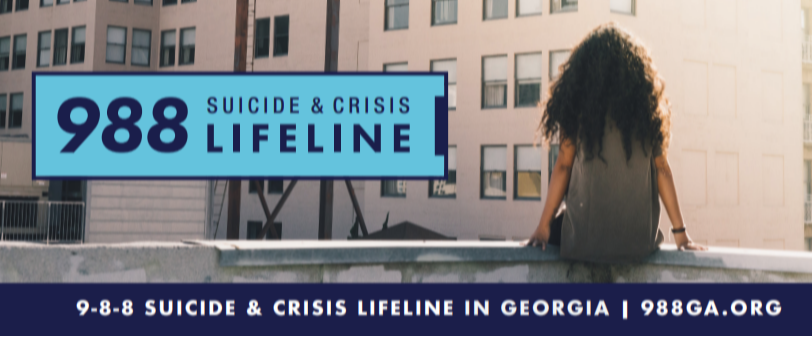 A person sits on a rooftop overlooking a large billboard that reads “988 Suicide & Crisis Lifeline.” A banner along the bottom reads, “9-8-8 Suicide & Crisis Lifeline in Georgia | 988GA.org.”