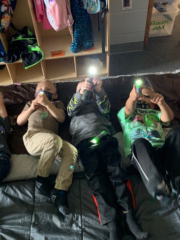 Four children sitting on a bed, each engrossed in their own phone.