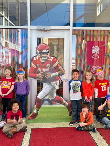 A group of children posing in front of a photo of a football player