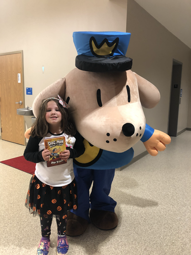 A little girl standing next to a large stuffed animal