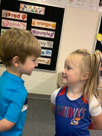 Two young children chatting in a classroom.