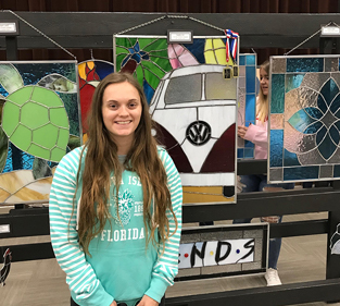 A girl standing in front of a display of stained glass