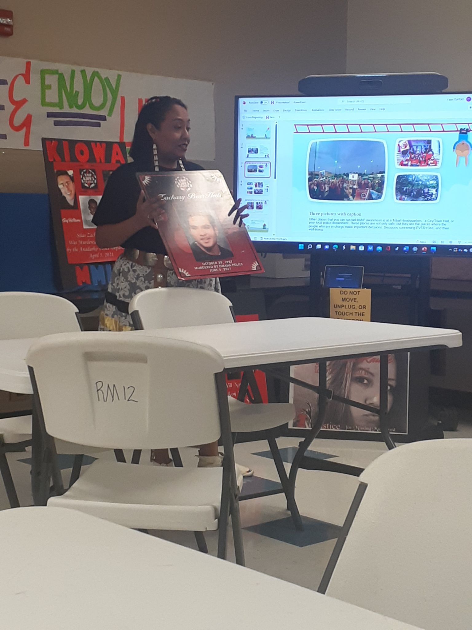 A woman standing in front of a table with a large screen.