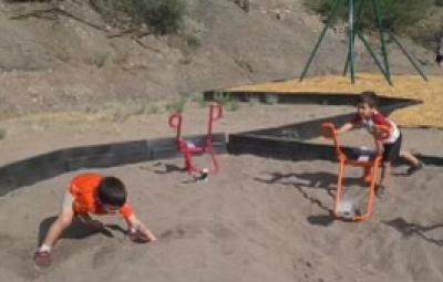 Children happily playing in the sand at a playground, building castles and enjoying the sunny day together.