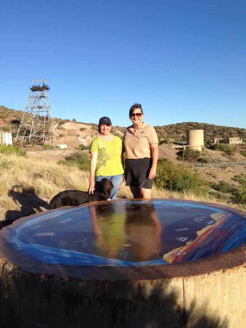 Two women stand beside a large circular object