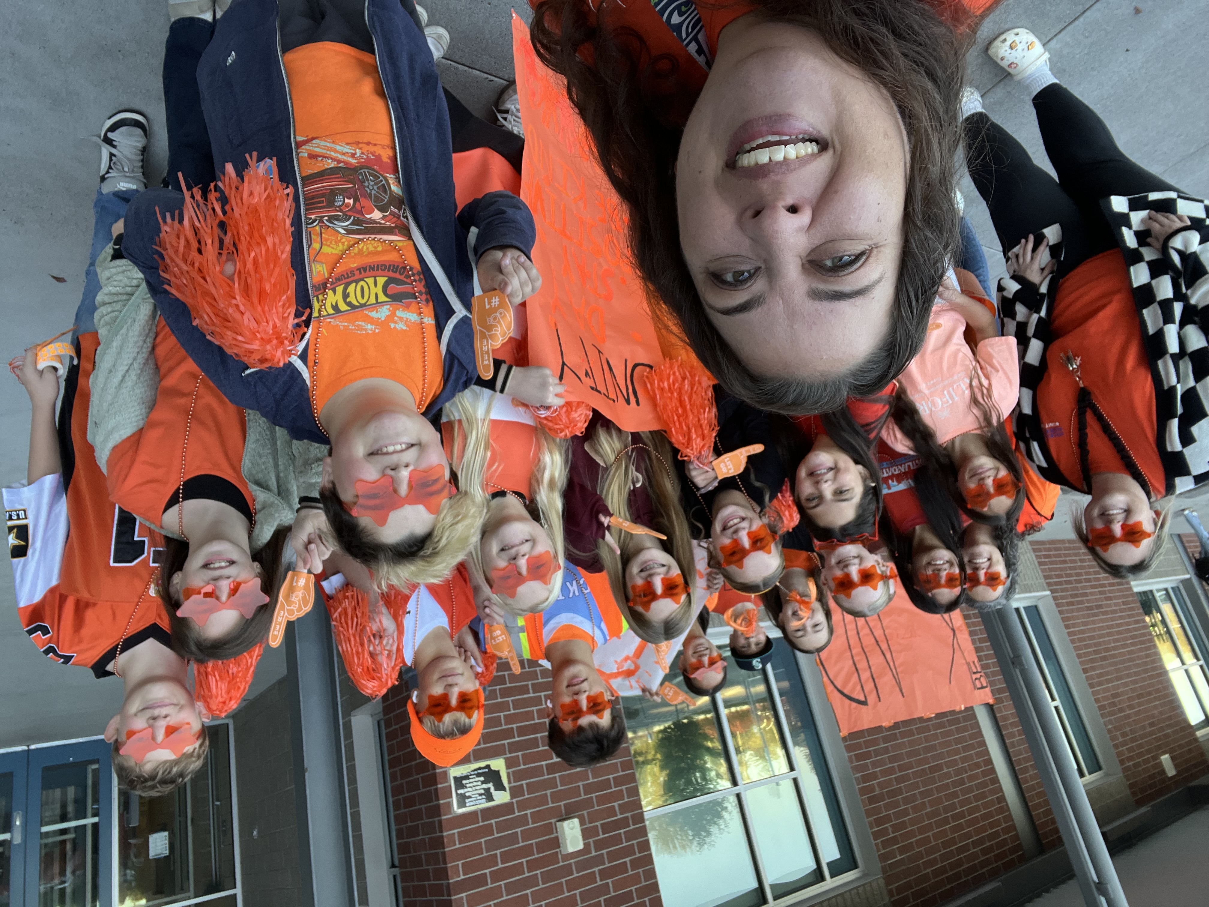 Selfie of students with the principal in school wearing orange