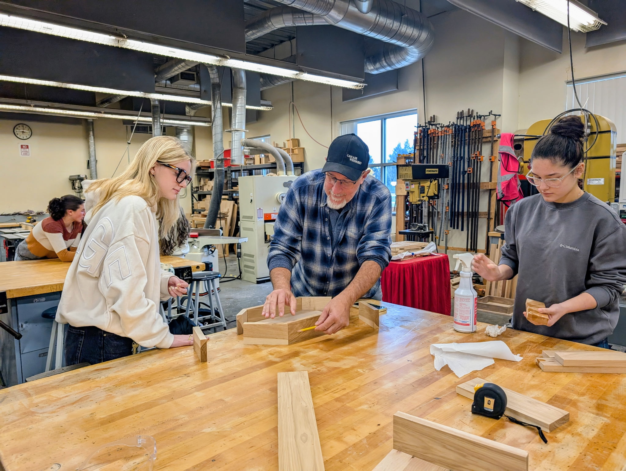 Two students and one teacher work in the woodshop