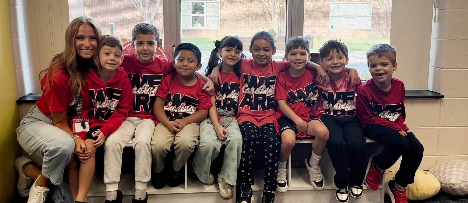 First graders lined up on a bench with their teacher.