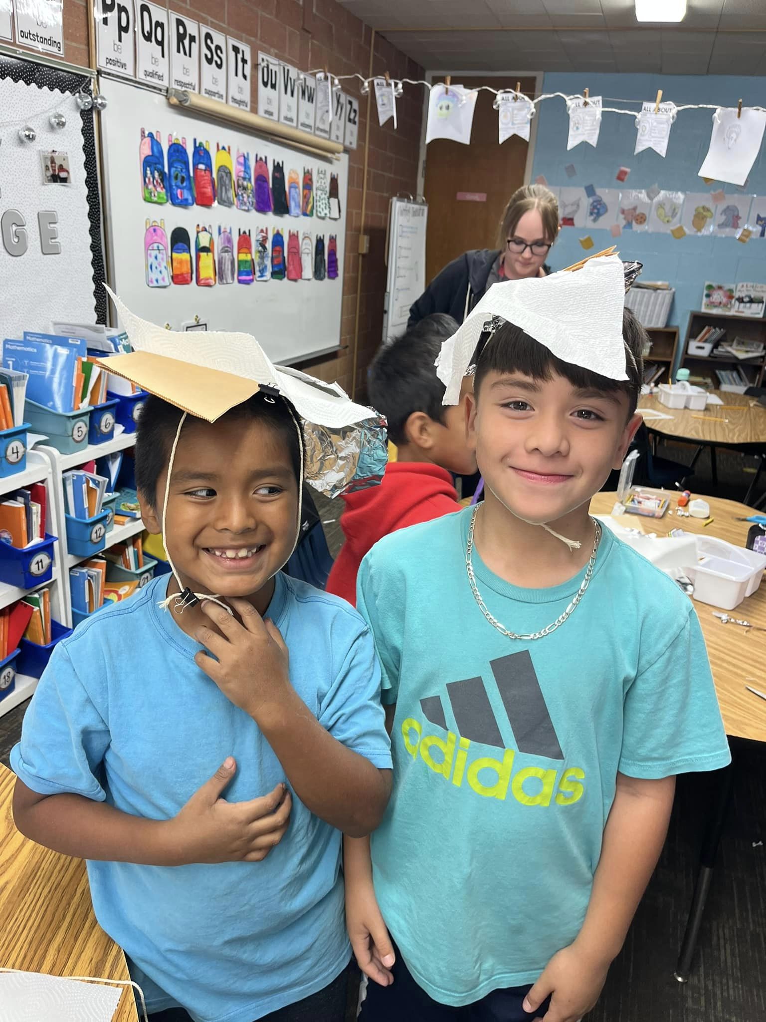 Two students wearing paper hats