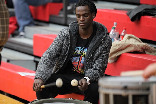A man sitting on a bench playing a drum
