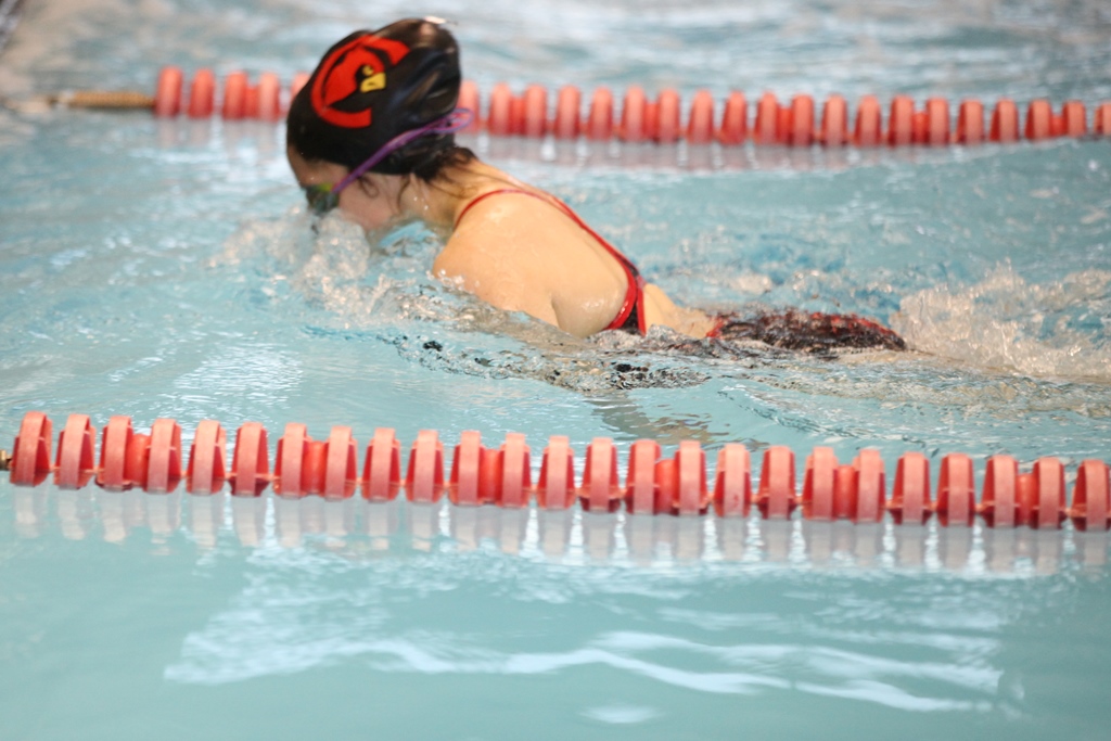 Woman in red swimsuit swimming in pool.