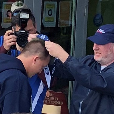 A man receiving a medal while the other guy is capturing the moment.