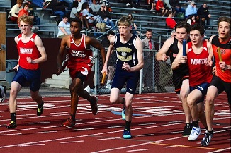 A group of young men sprinting on a track during a race.