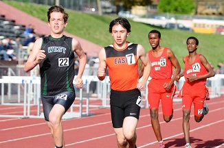 A group of young men sprinting on a track during a race.