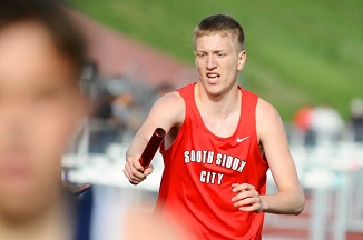 A young man in a red shirt is sprinting energetically across an open field, showcasing determination and vitality.