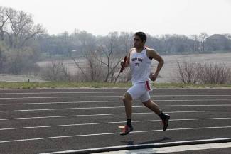 A man running on a track with a ball in hand.