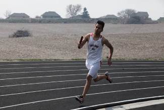 A male athlete sprinting on a track, showcasing determination and athleticism during a competitive race.