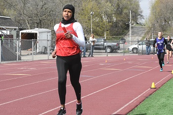 A woman running on a track with other people during a race.