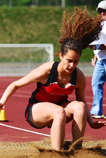 A girl in a red and black outfit jumping in the air.