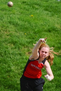 A girl skillfully throws a discus into the air, showcasing her athleticism and focus during a track and field event.