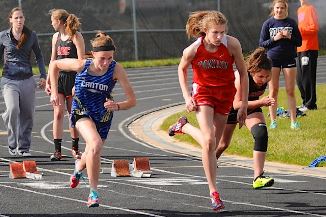 Several girls running on a track during a race.