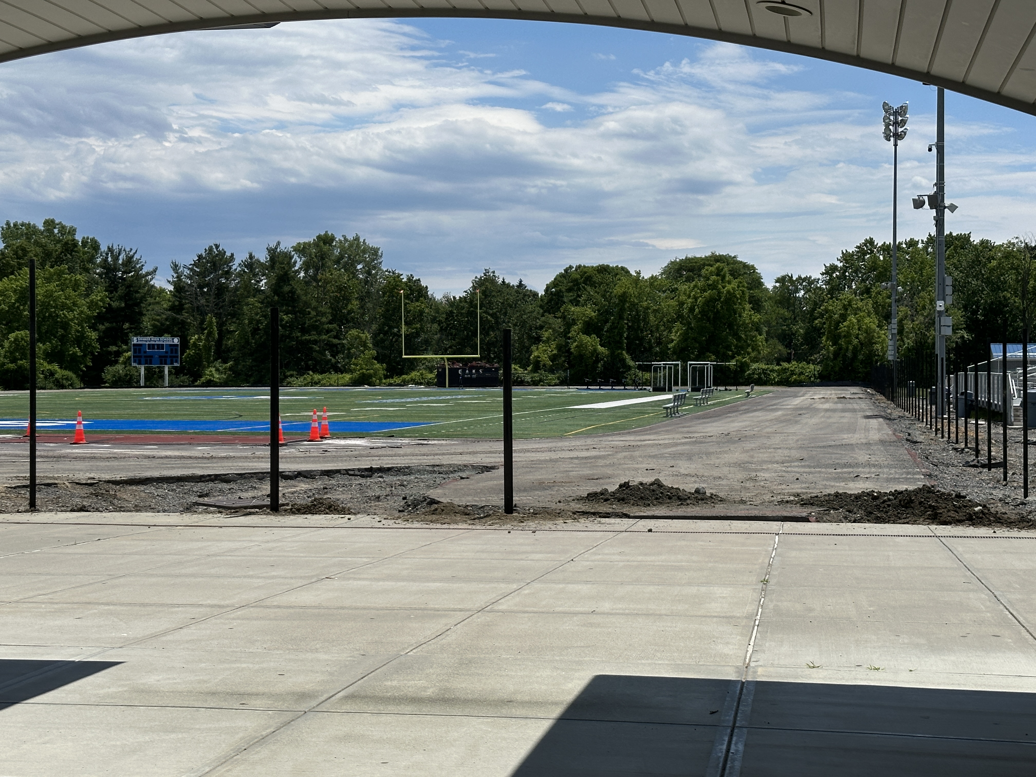 An image of a torn up track with mounds of dirt and metal fence posts.