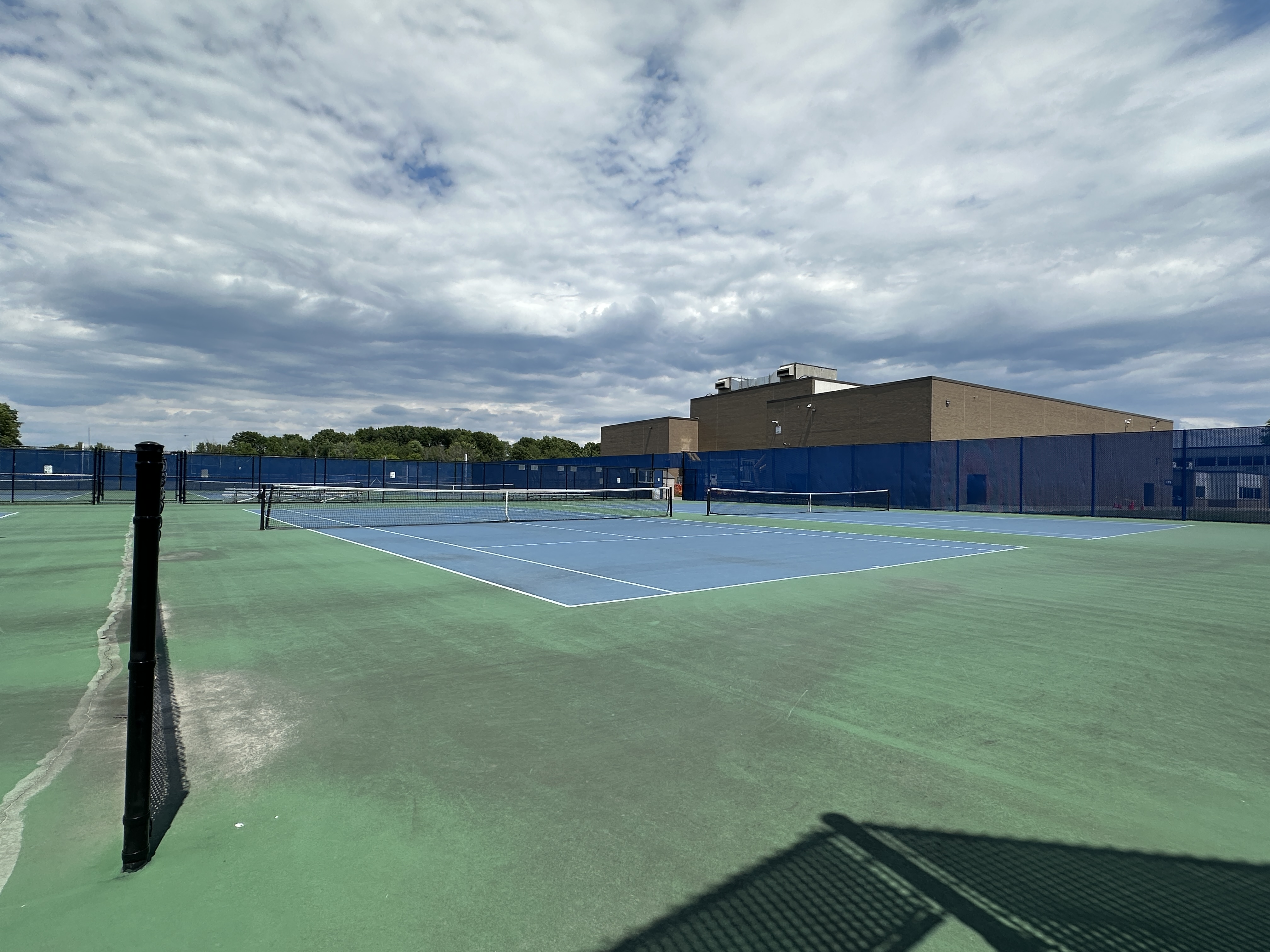 An image of tennis courts with Shaker High School in the background.