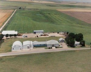 Aerial view of a farm showcasing multiple buildings surrounded by fields and greenery, illustrating rural life and agriculture.