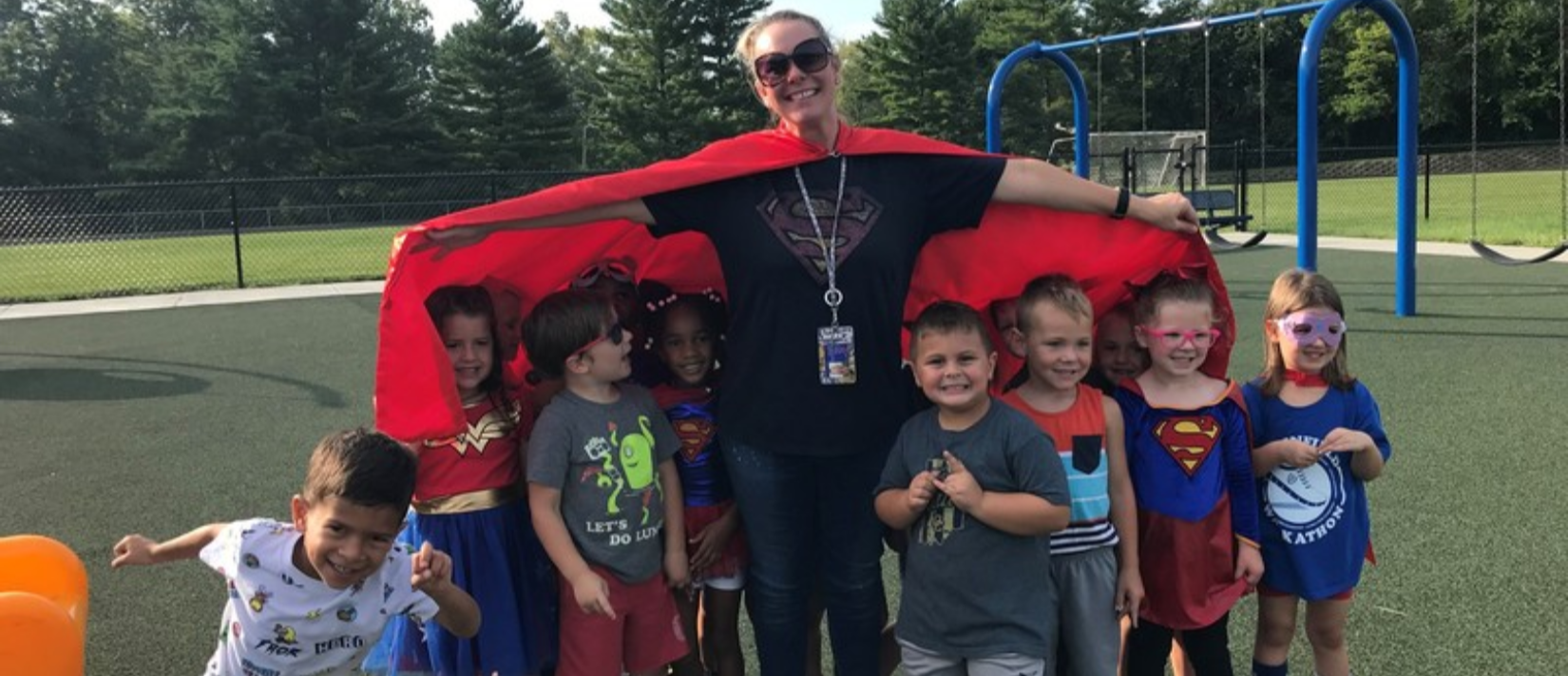 photo of teacher with students outside on the playground