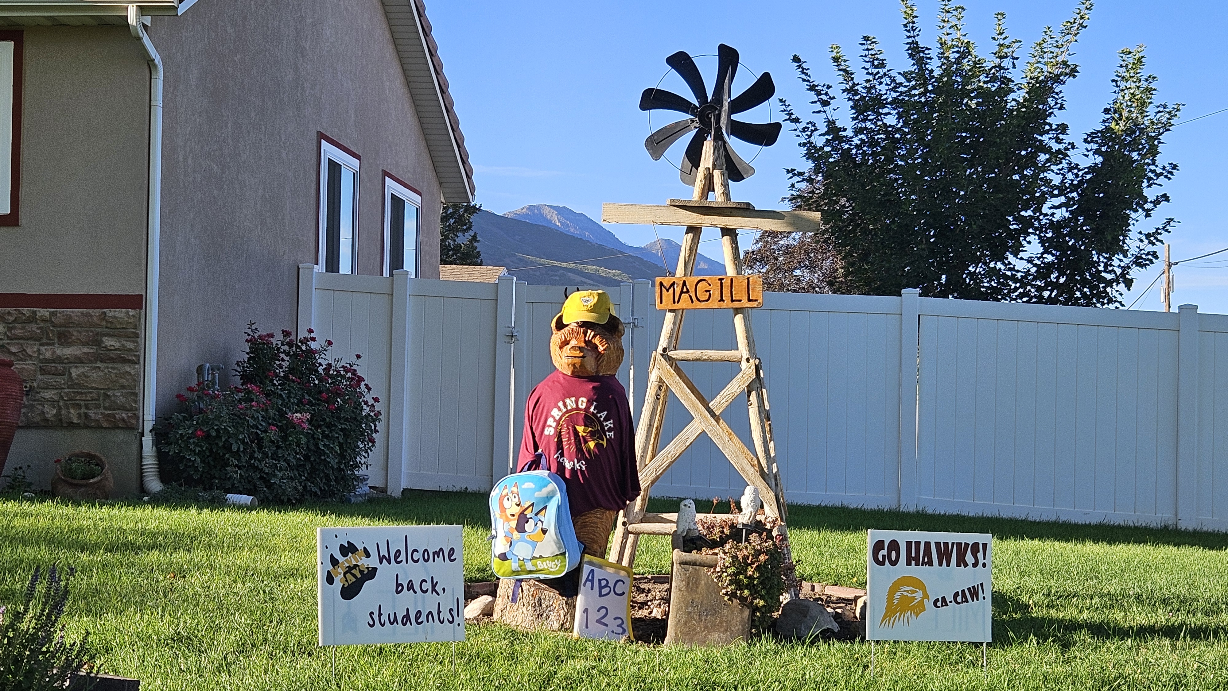 a wooden bear wearing a spring lake shirt in a neighbors yard