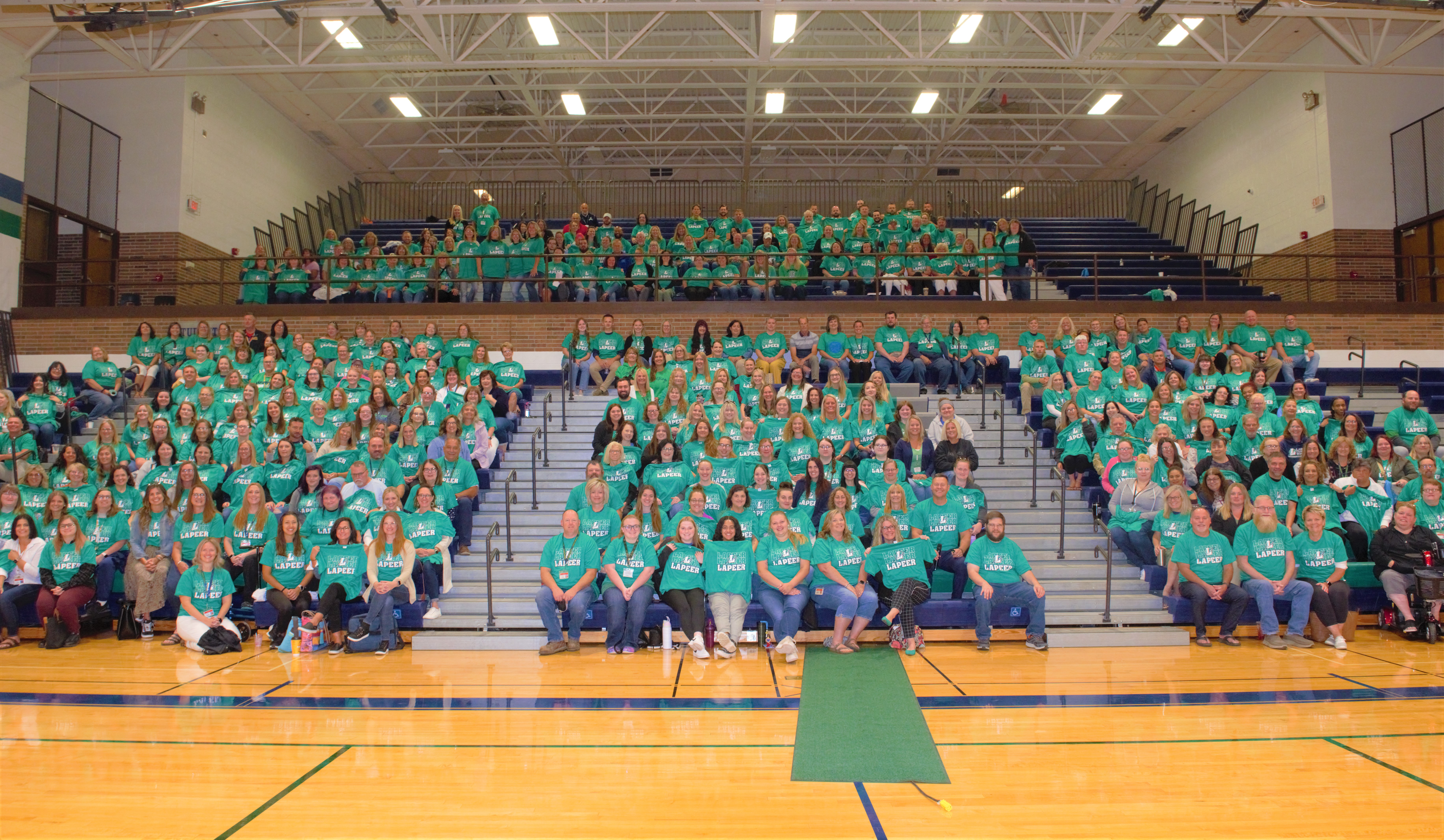 school district staff members in a gym posing for a group picture