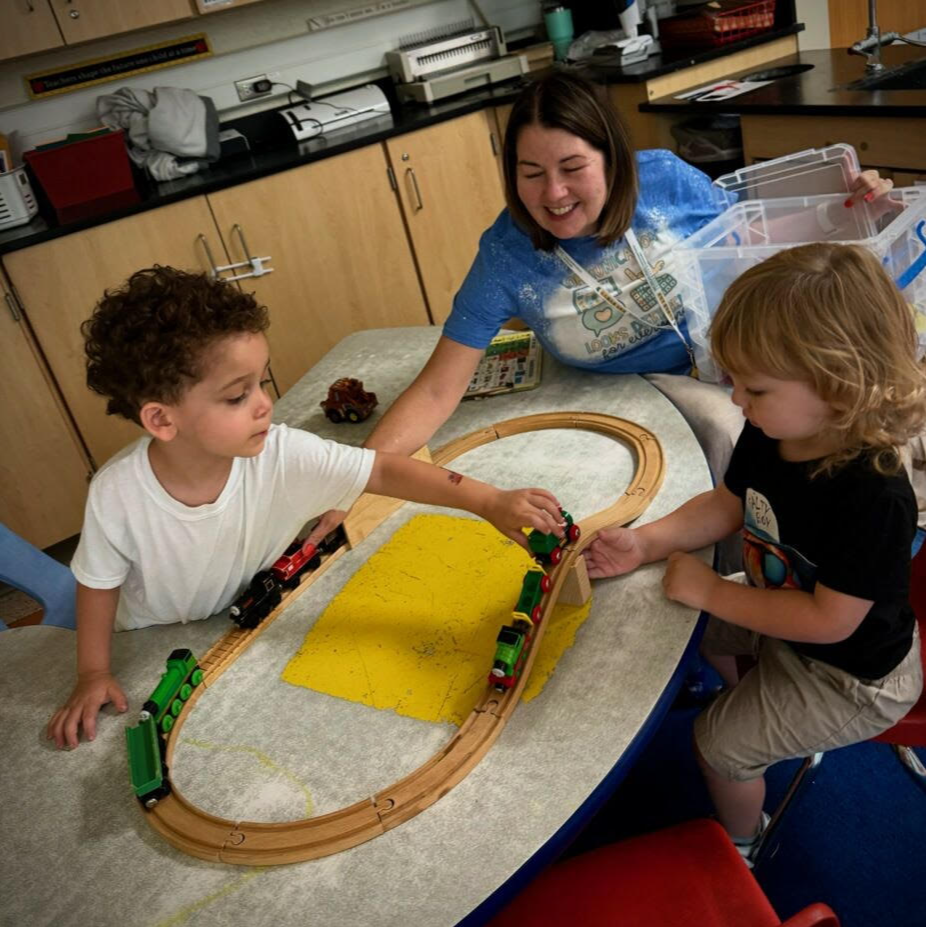 Woman helping two young children in a classroom