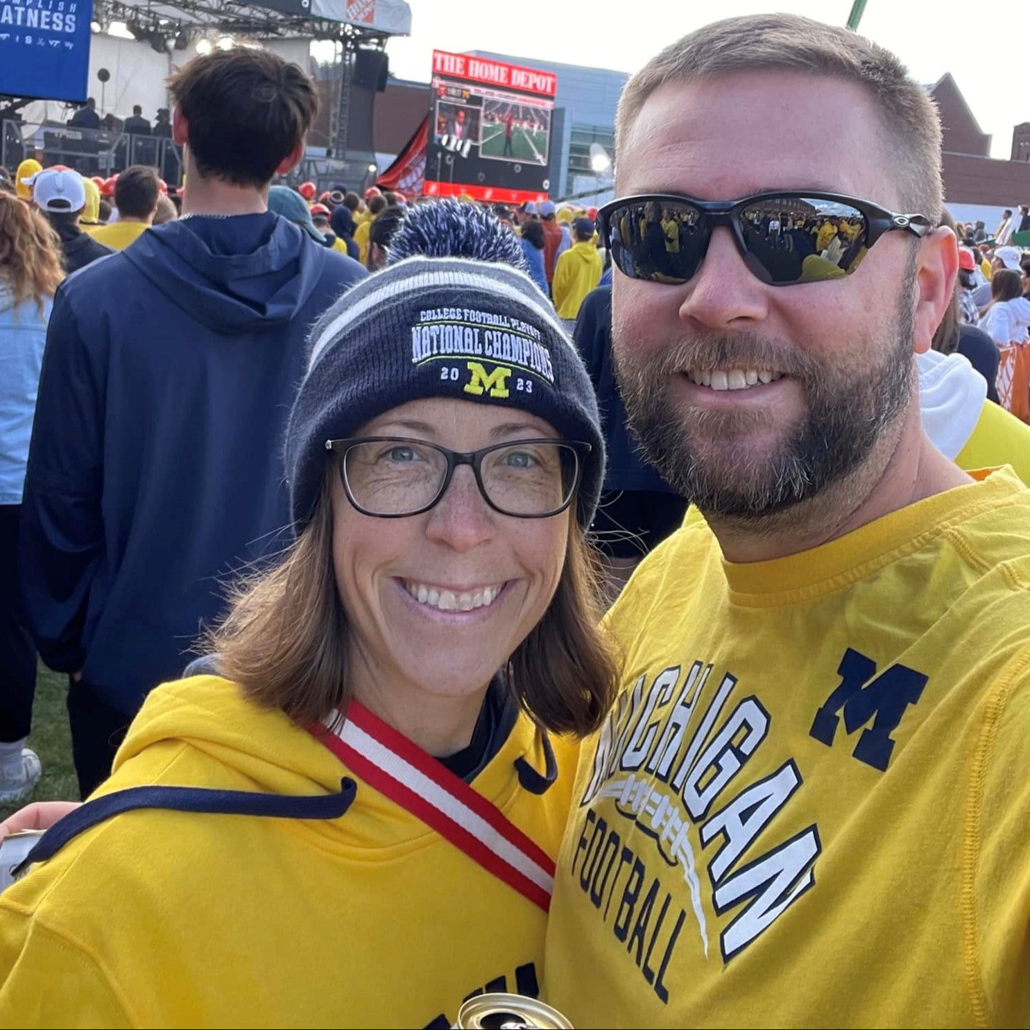 Husband and wife posing for a photo at a football game