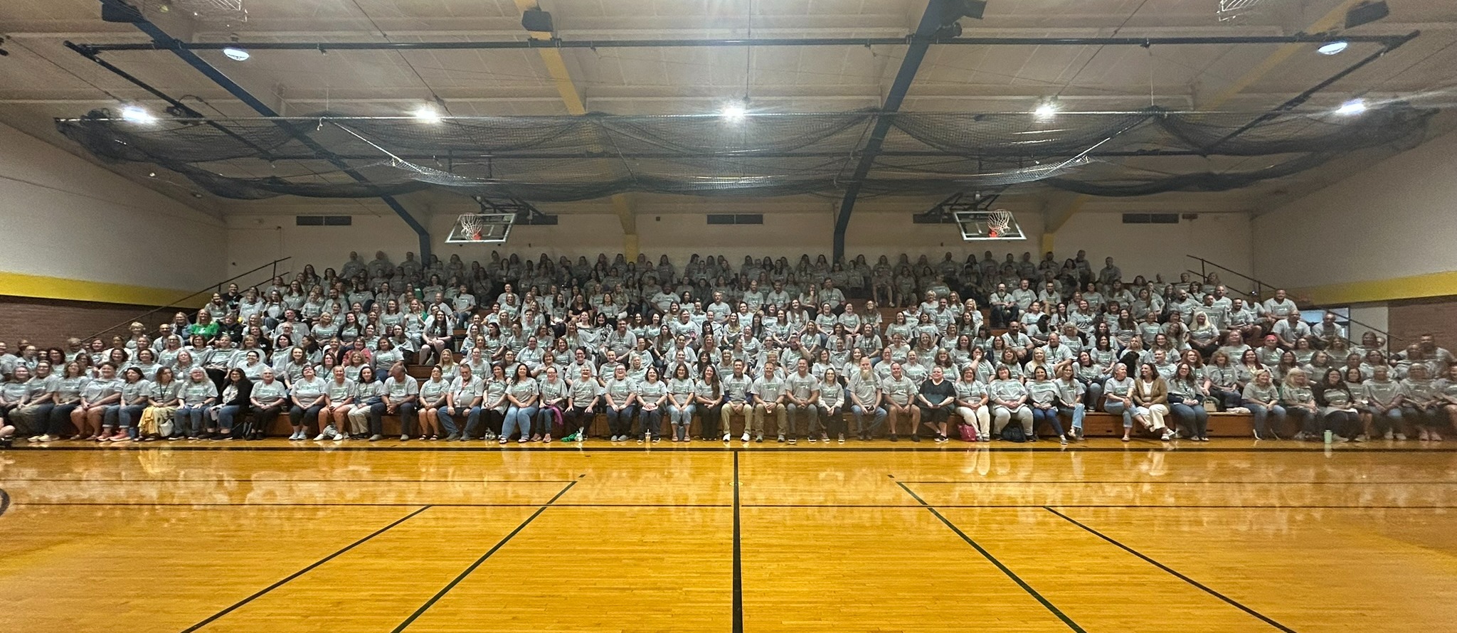 school district staff members in a gym posing for a group picture