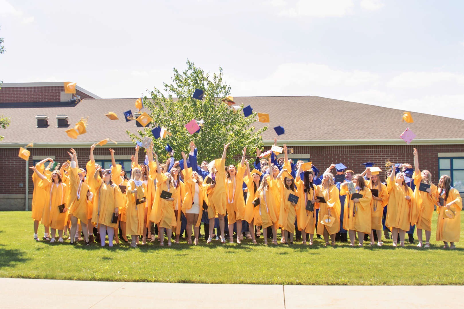 A diverse group of graduates proudly wearing caps and gowns, celebrating their academic achievements together outdoors.