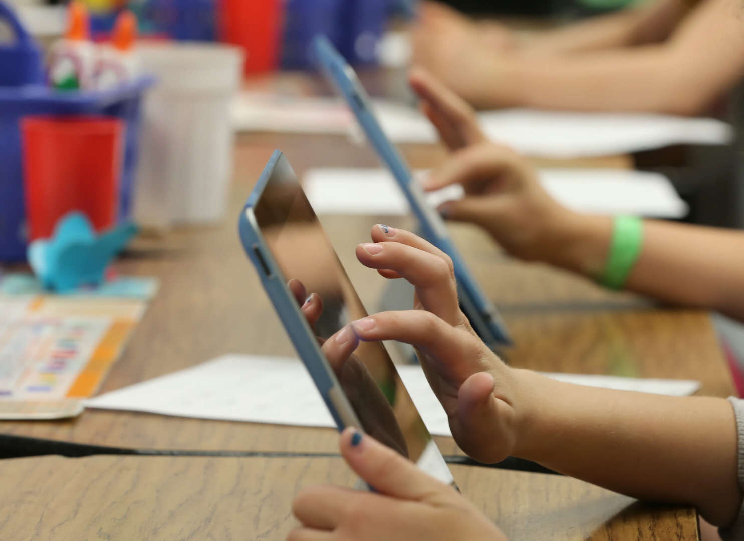 A group of people sitting at a table with ipads