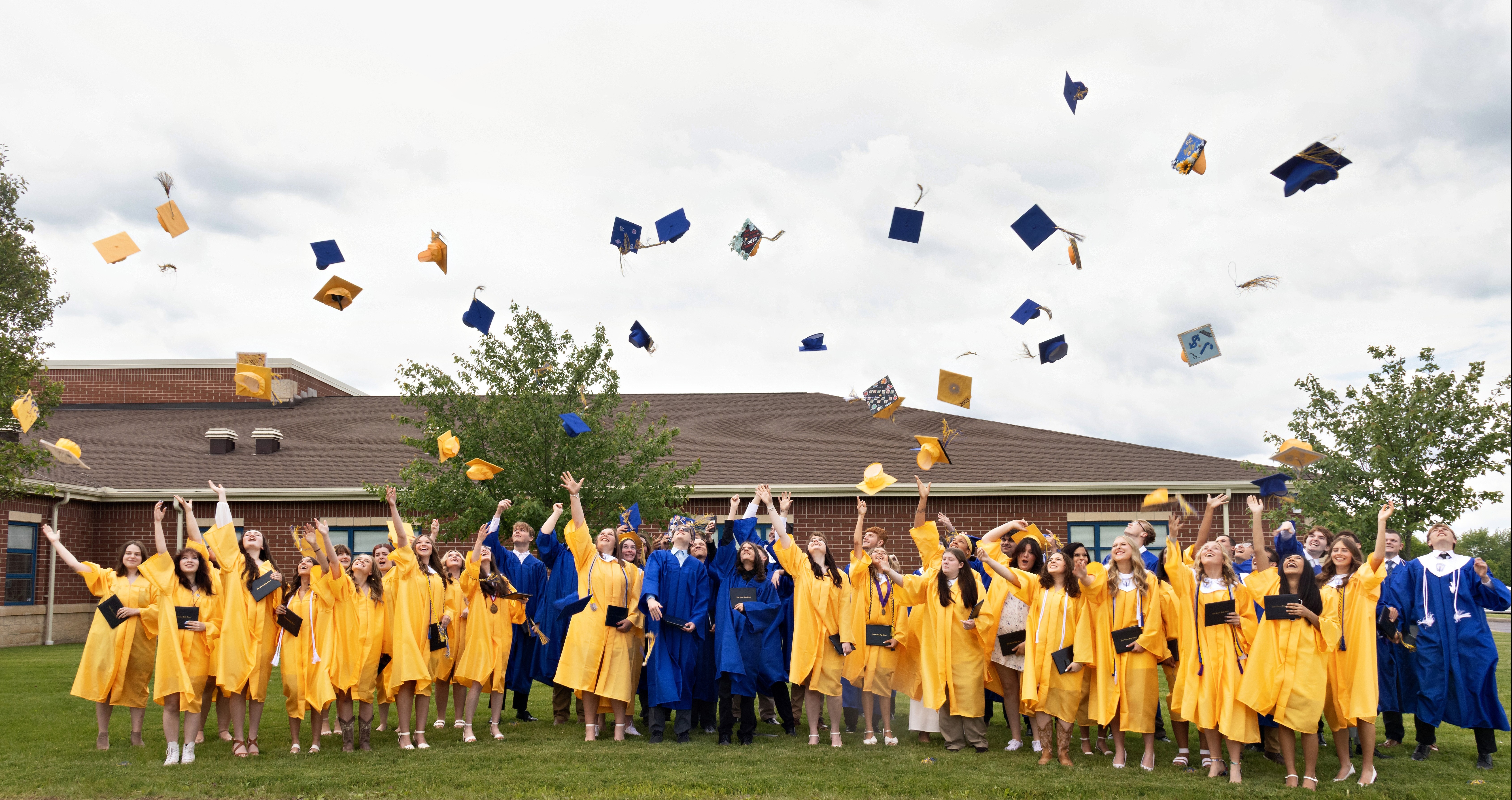 A diverse group of graduates proudly wearing caps and gowns, celebrating their academic achievements together outdoors.