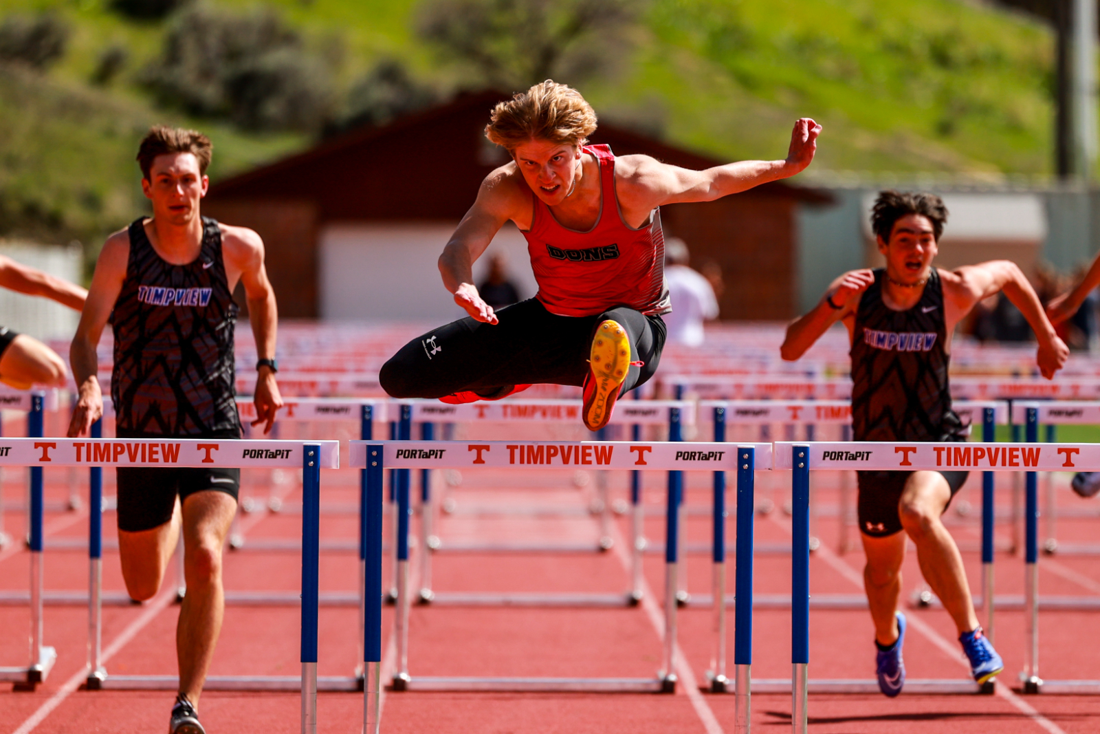 student jumping a bar in a track and field field