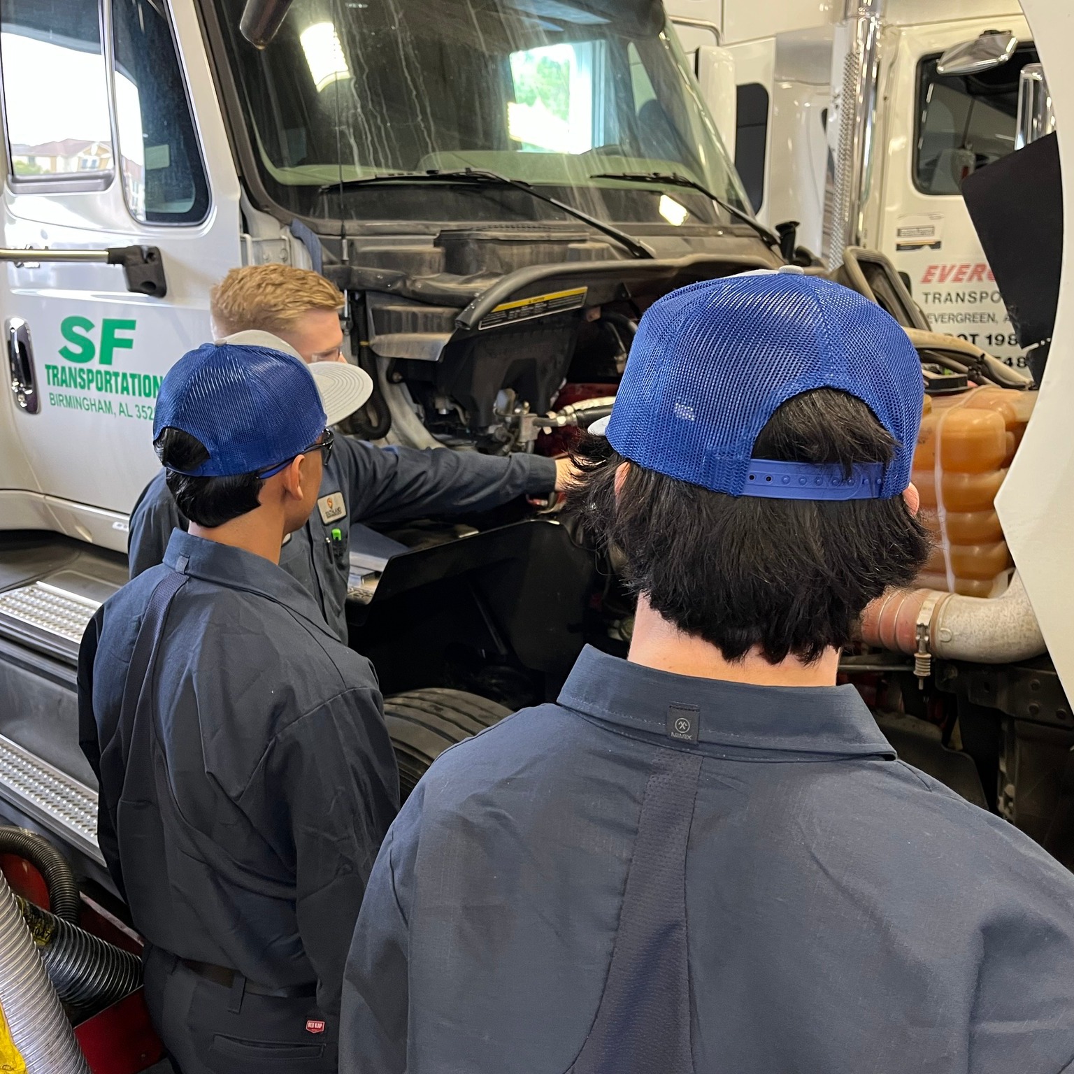 Students are working on the engine of a semi truck. 