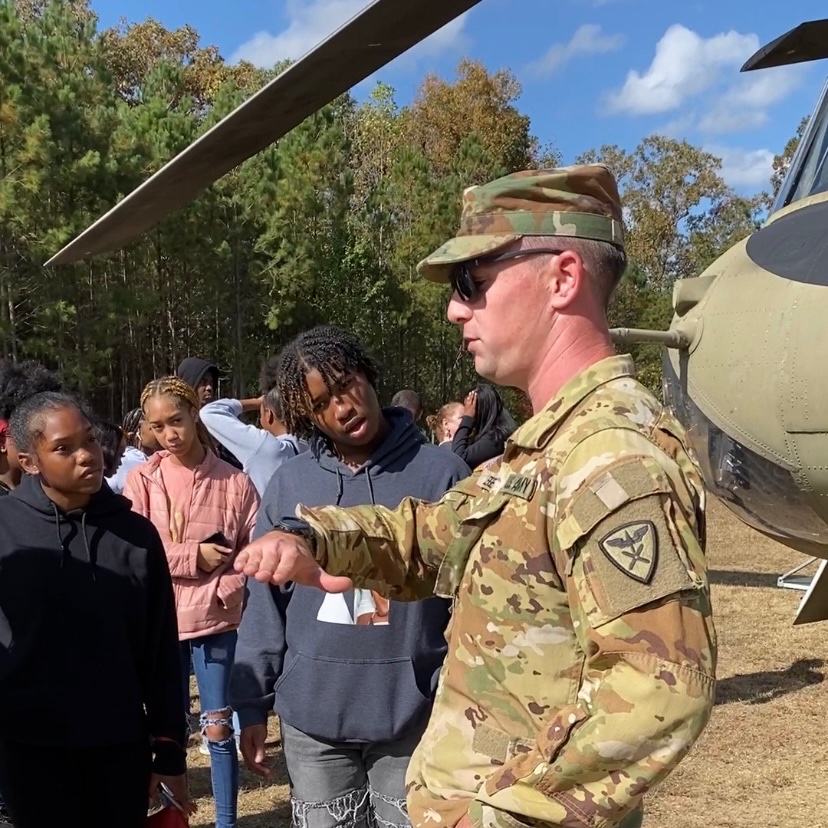 Member of the US Army speaks to students about how a helicopter lands. 