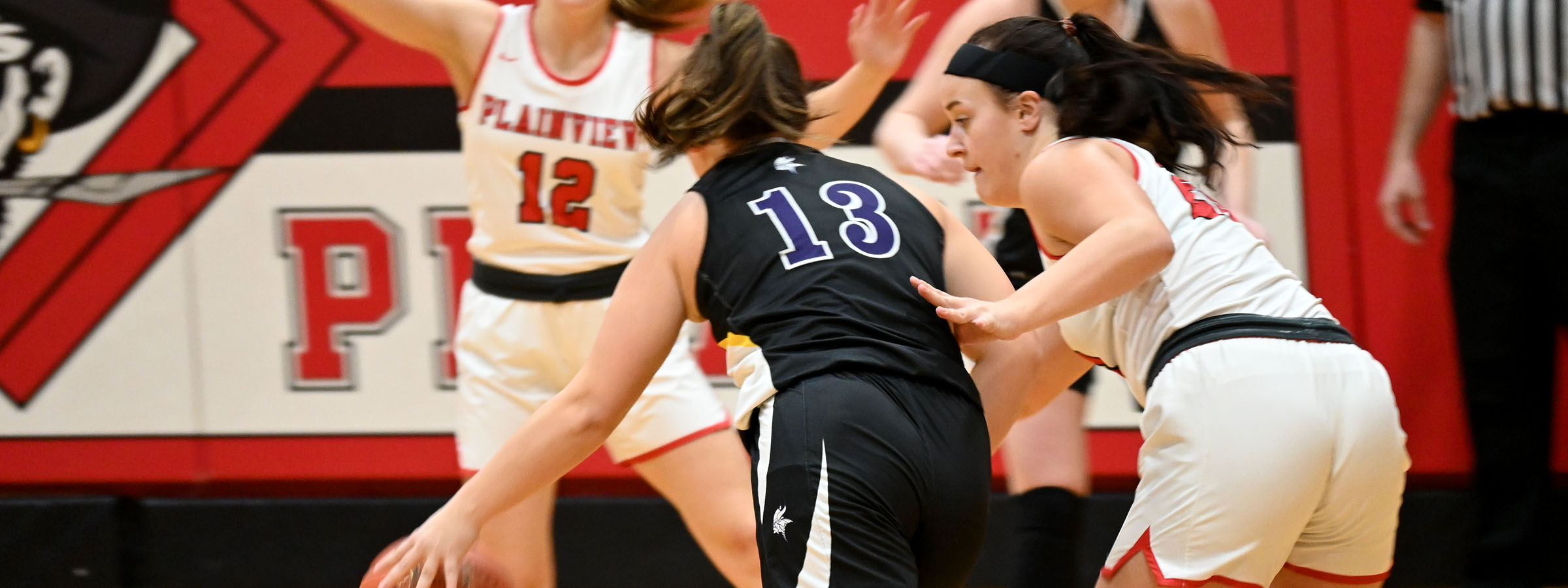 Two girls basketball players fiercely compete for possession of the ball on the court.