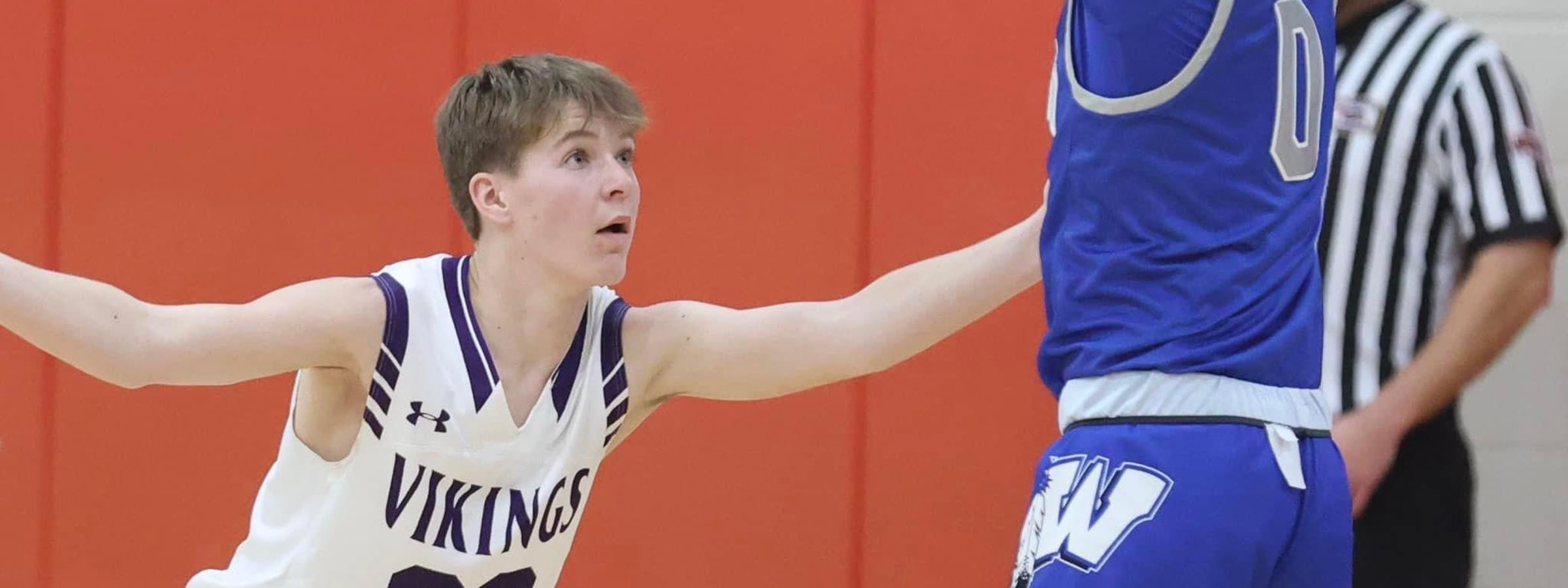 A young man in a white uniform preparing to shoot a basketball on the court.