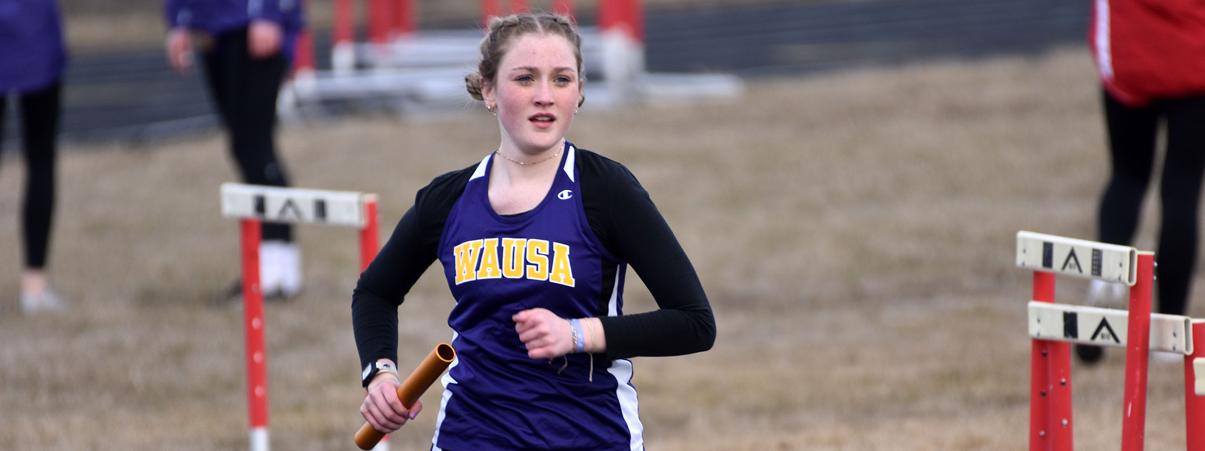 A young girl sprinting in a race with a baton.