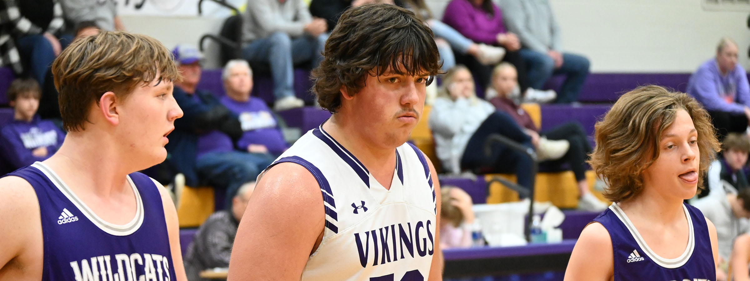 Young men in purple uniforms standing on the court, ready to play basketball.