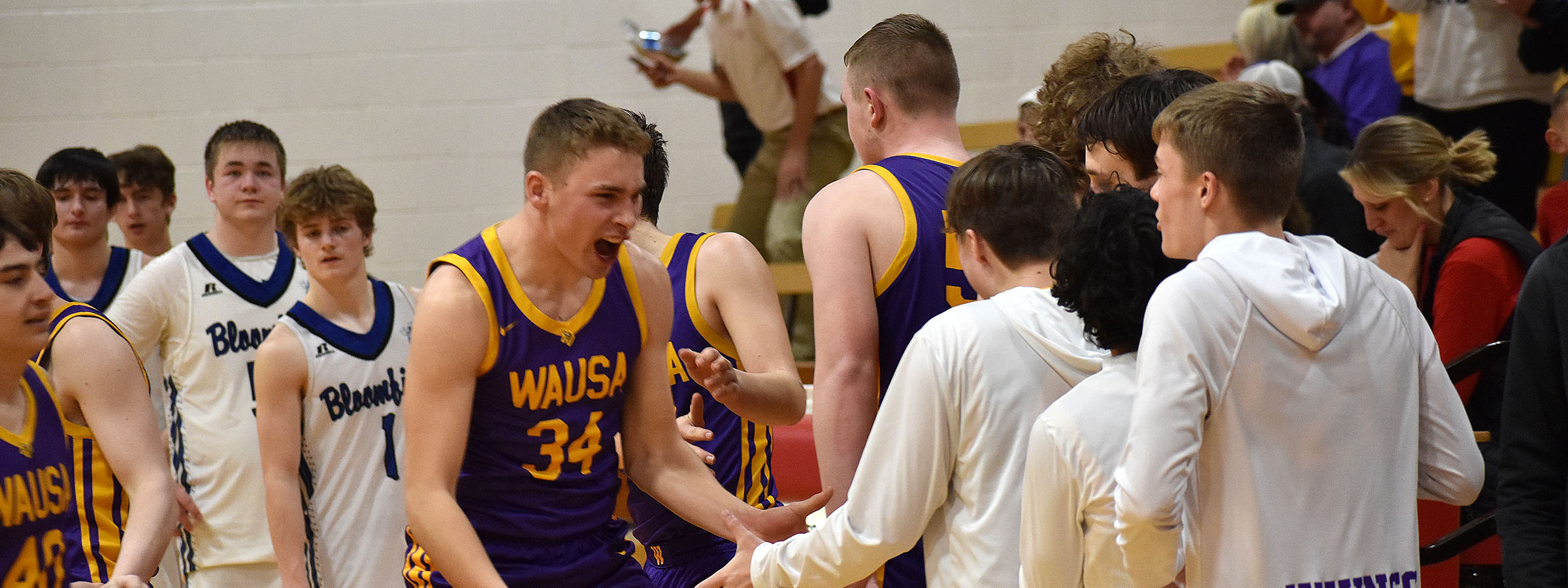  A group of young men in purple and gold uniforms posing for a team photo on the basketball court.