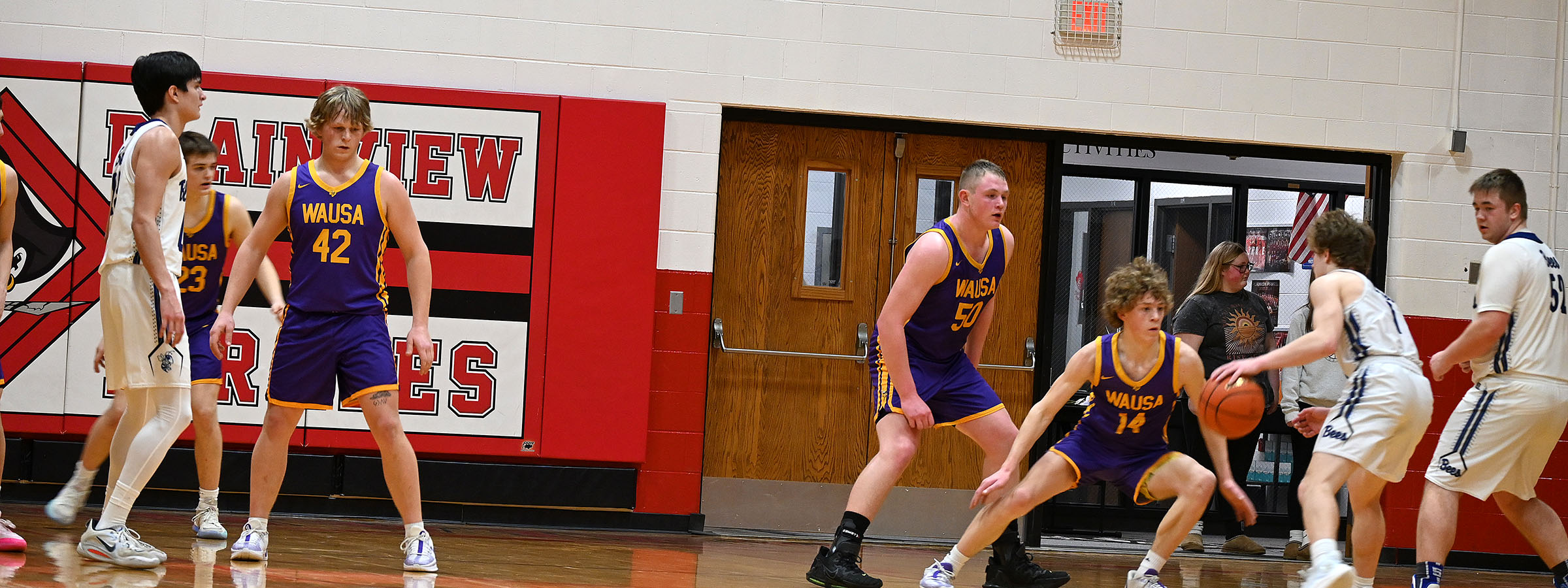 A high school boys basketball game in action, with players dribbling and shooting on the court, showcasing teamwork and energy.