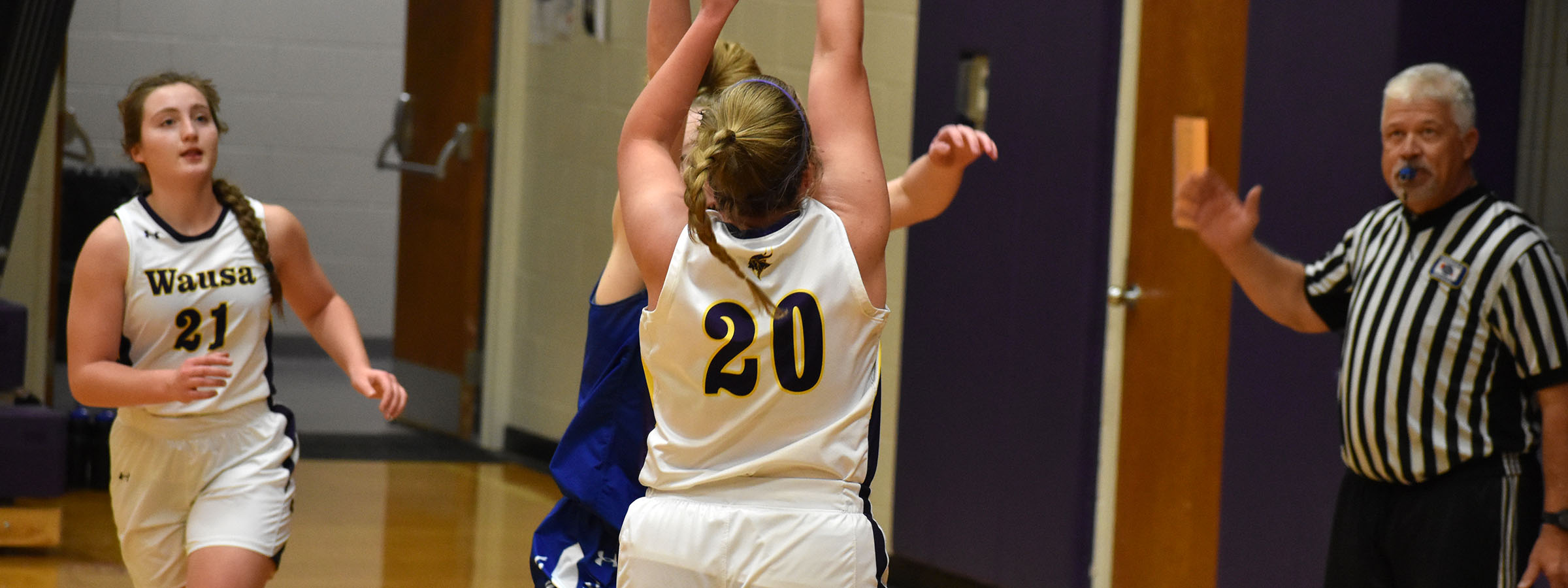 A girl in a white uniform reaching for the ball.