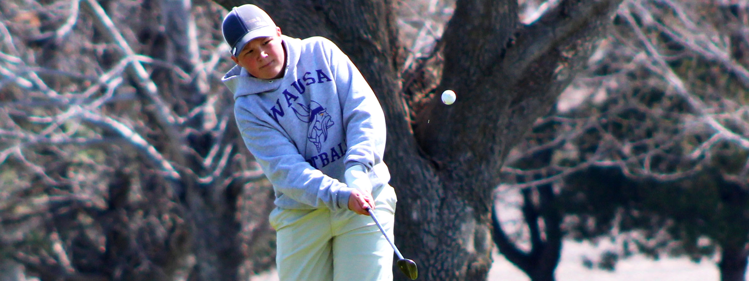 Golfer swinging club on green grass.