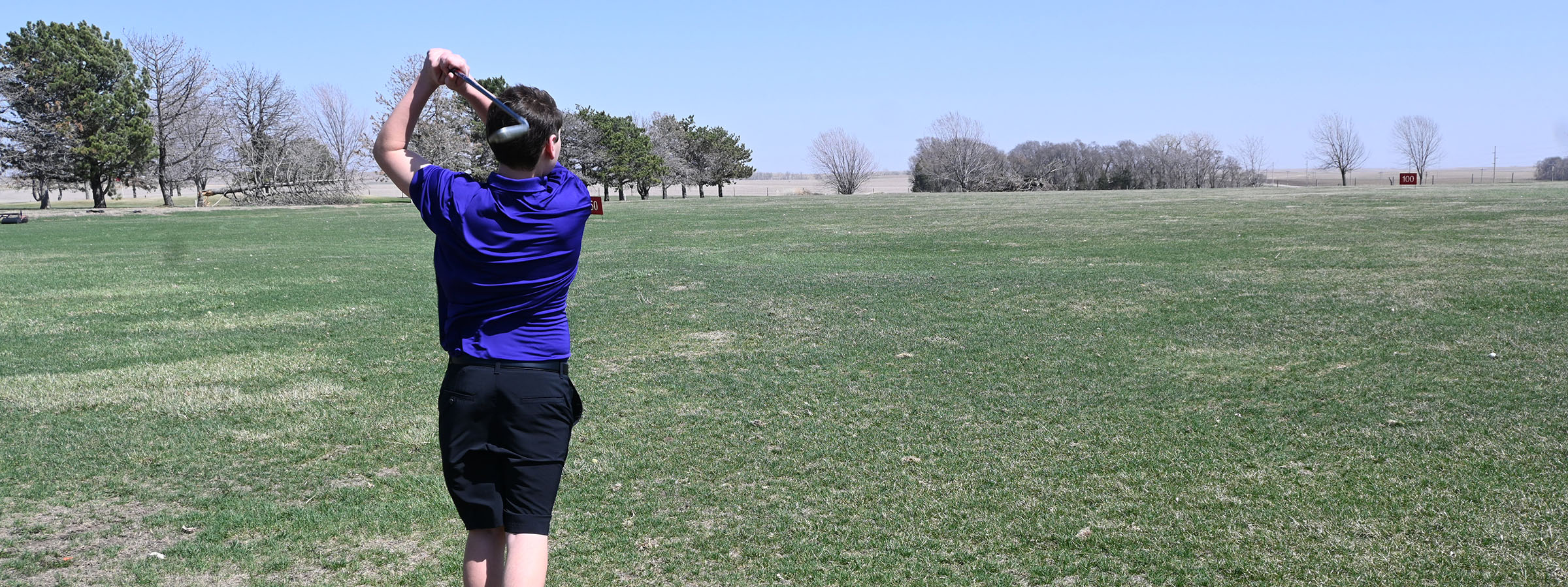 A man in a purple shirt joyfully leaps into the air.