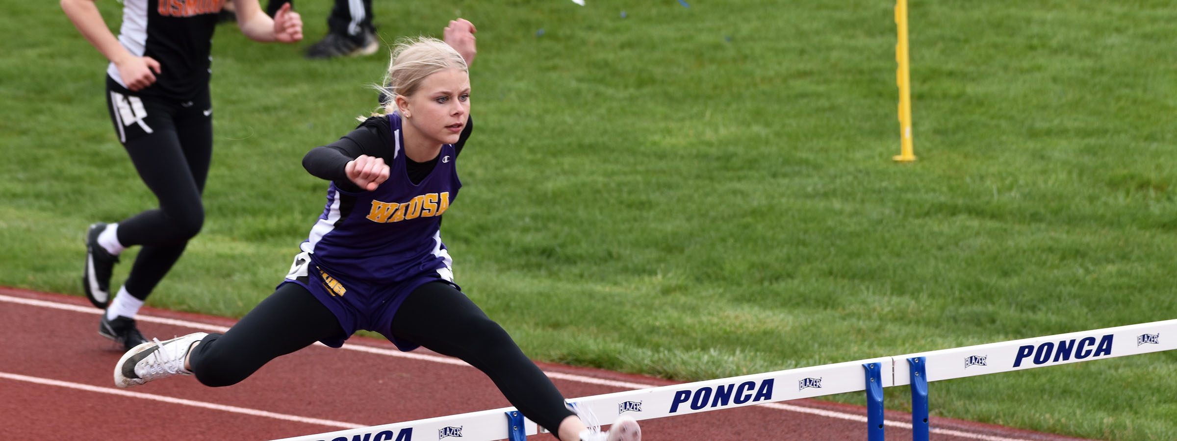 A girl leaping over a hurdle during a race.